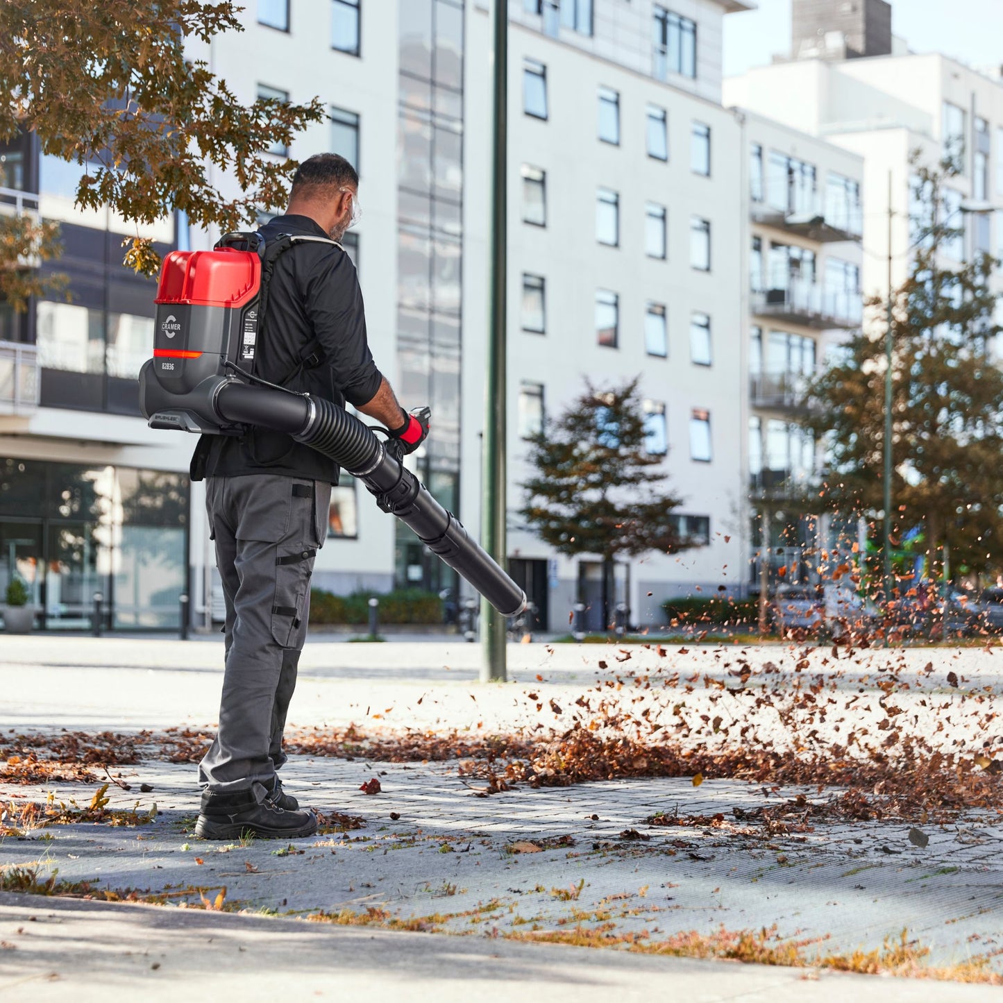 Person using a backpack leaf blower on a city street