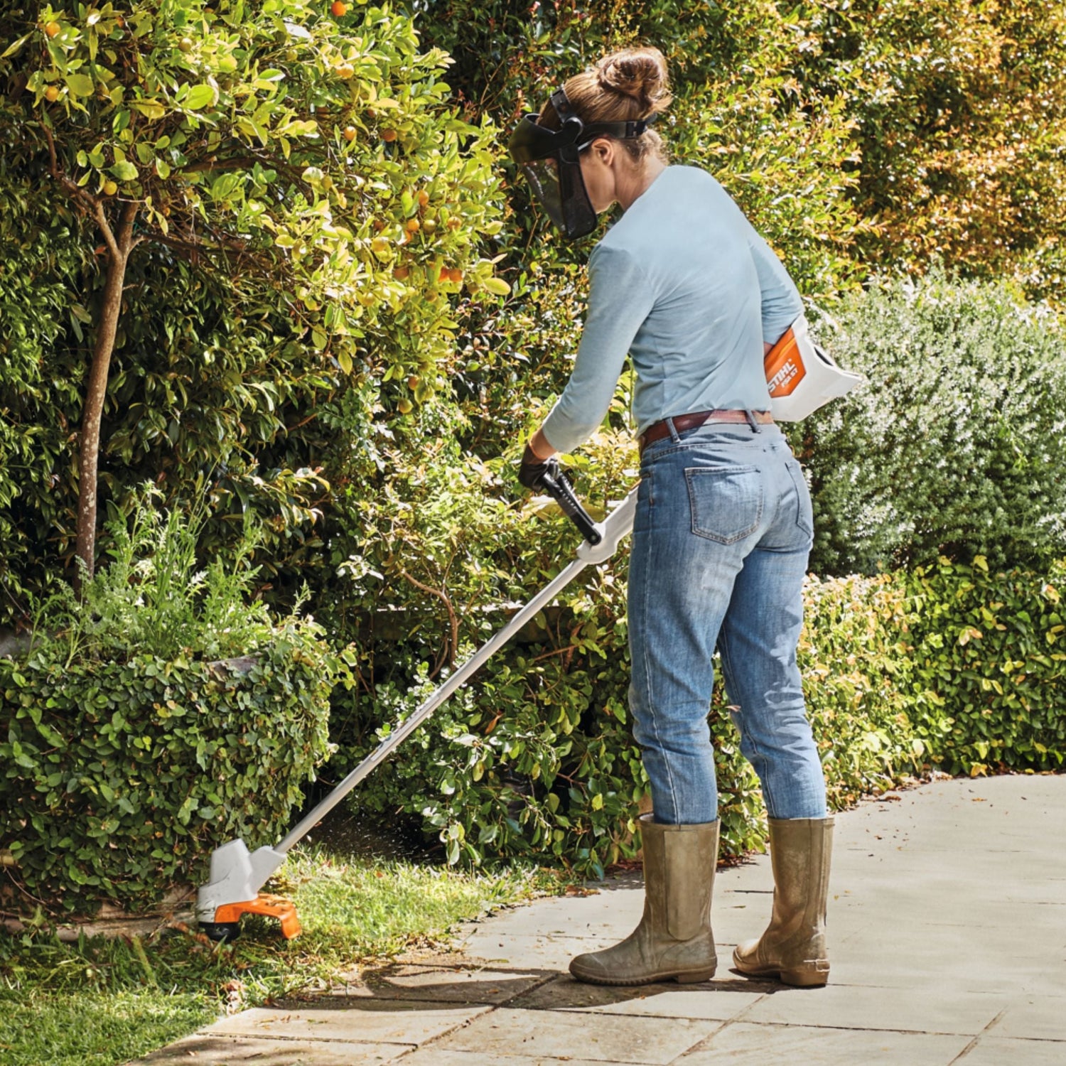 woman using white and orange brushcutter