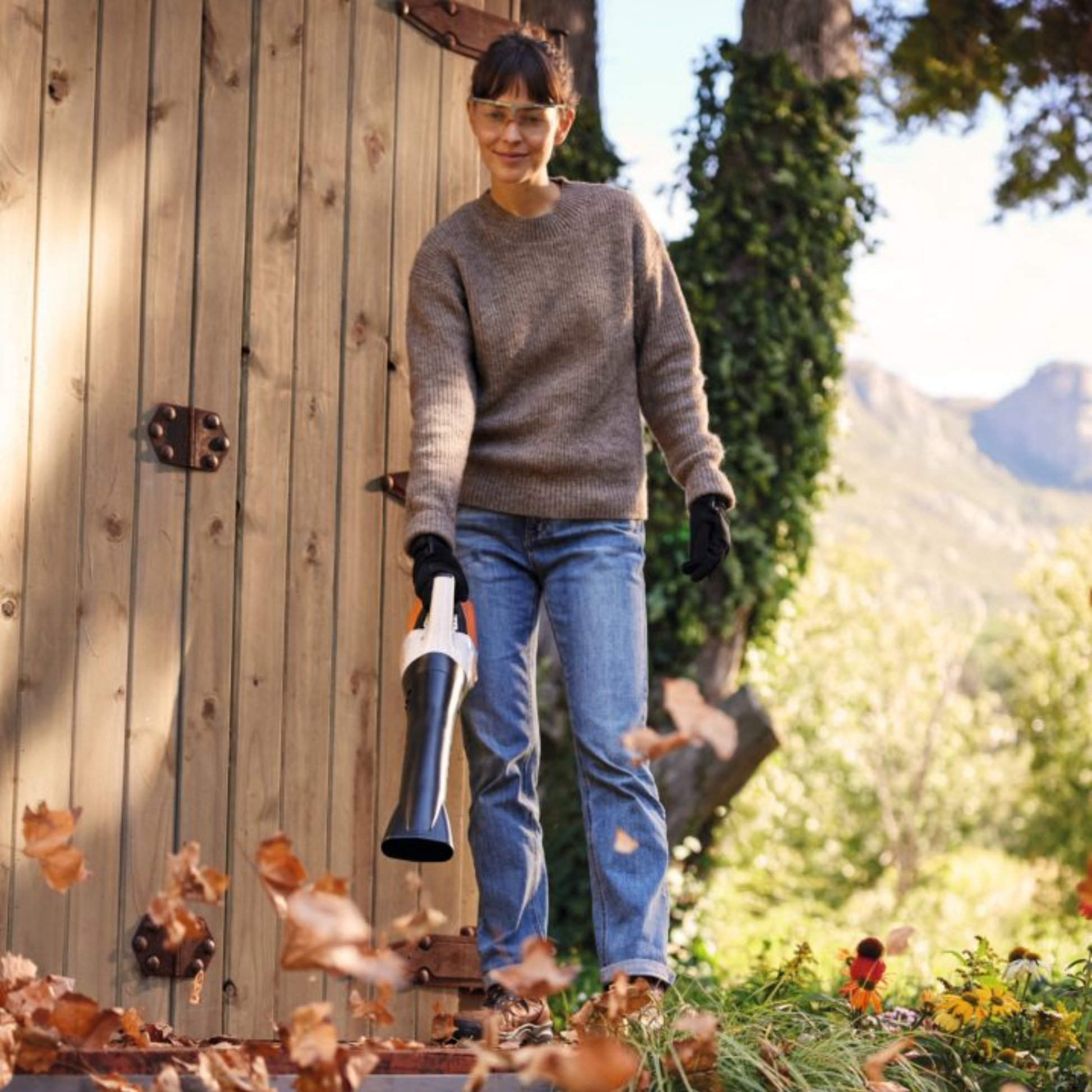 woman using stihl leaf blower to clear leaves from patio
